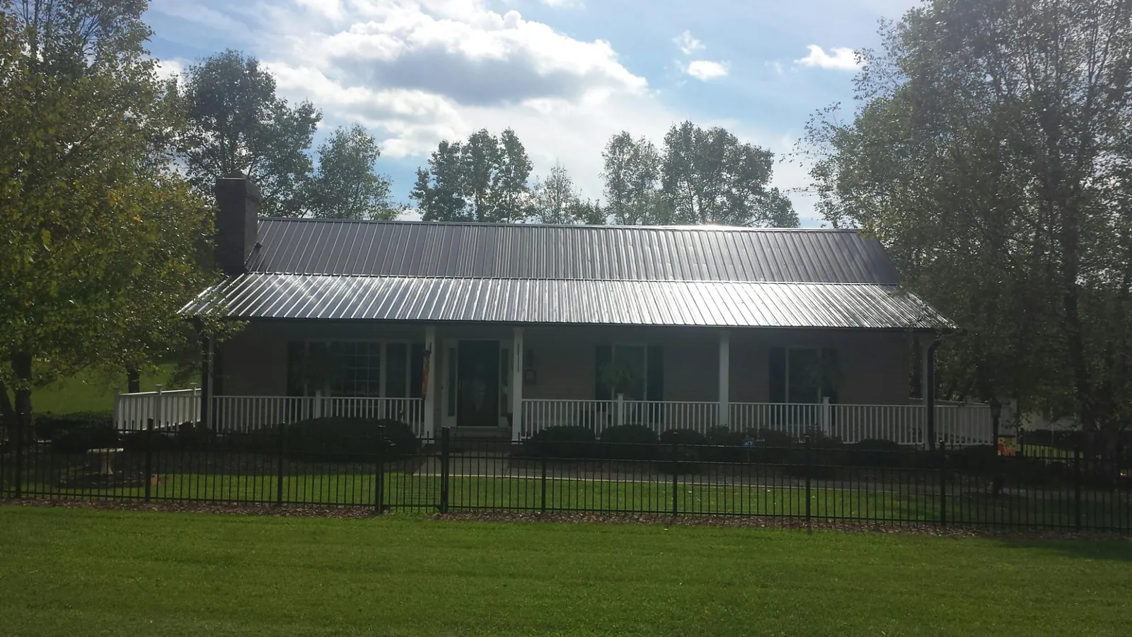 Gray metal roof on a brick ranch with a full width front porch — Gutter Guard Installation work by our crew in Franklin